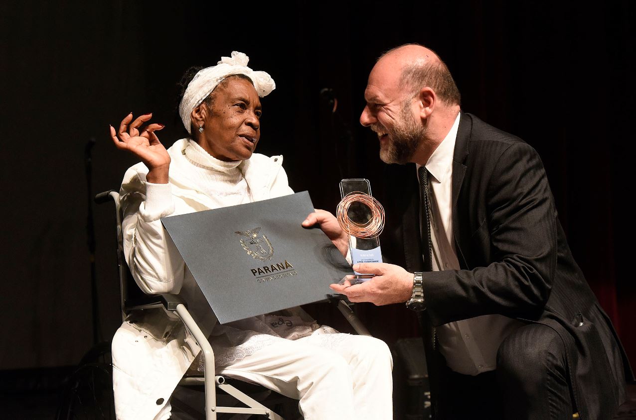 Vó Neli de Oxalá recebeu o troféu das mãos do secretário da Cultura, João Luiz Fiani.